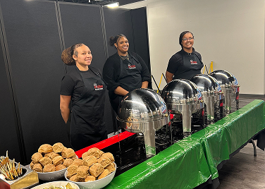 Caterers standing behind table full of food