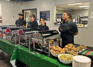 Caterers standing behind table full of food